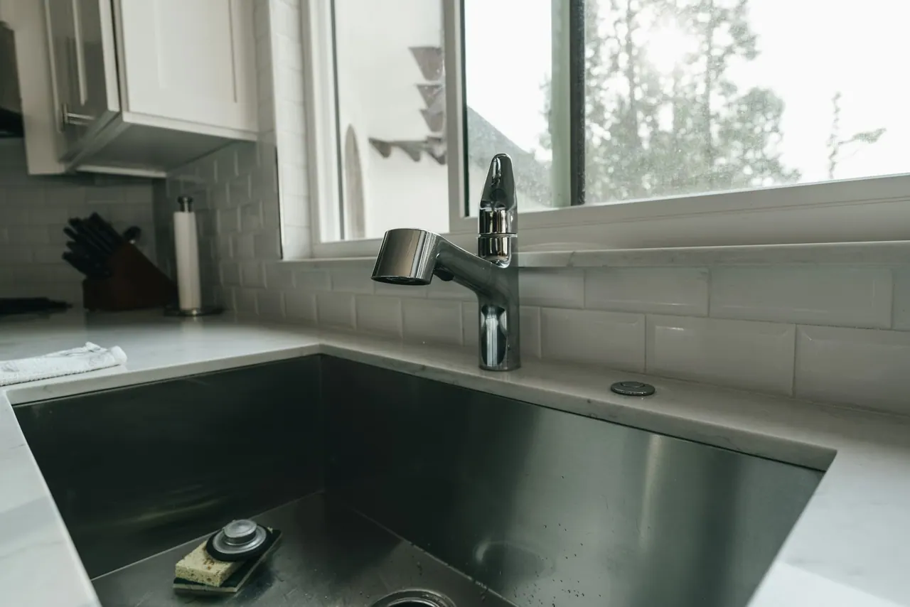 A clean kitchen sink and tap under a bright window