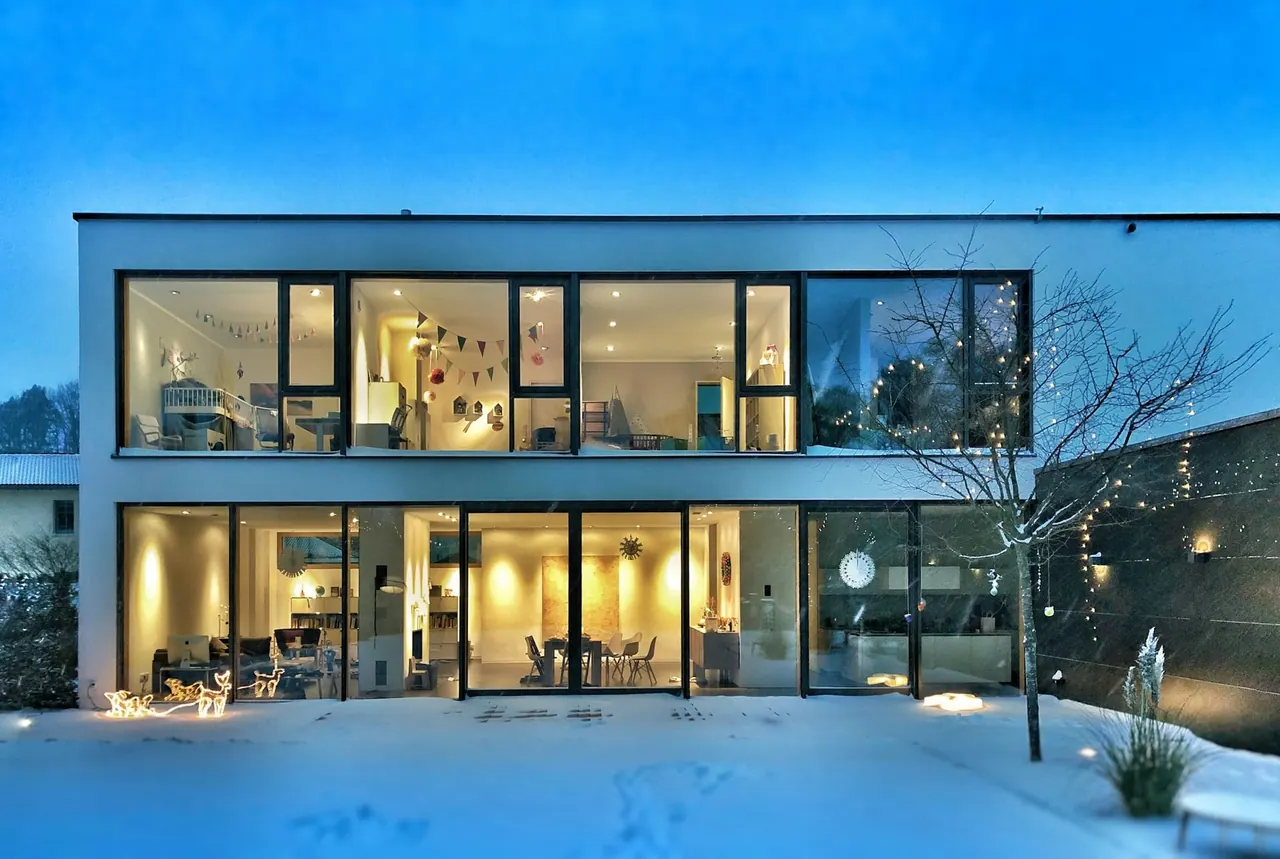 A two storey modern house at dusk with every window lit