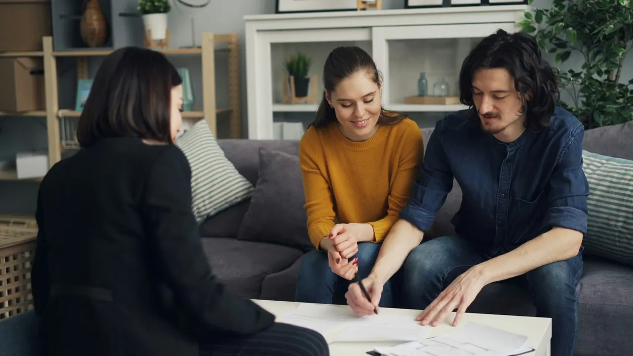 An agent going through papers with a couple on their sofa