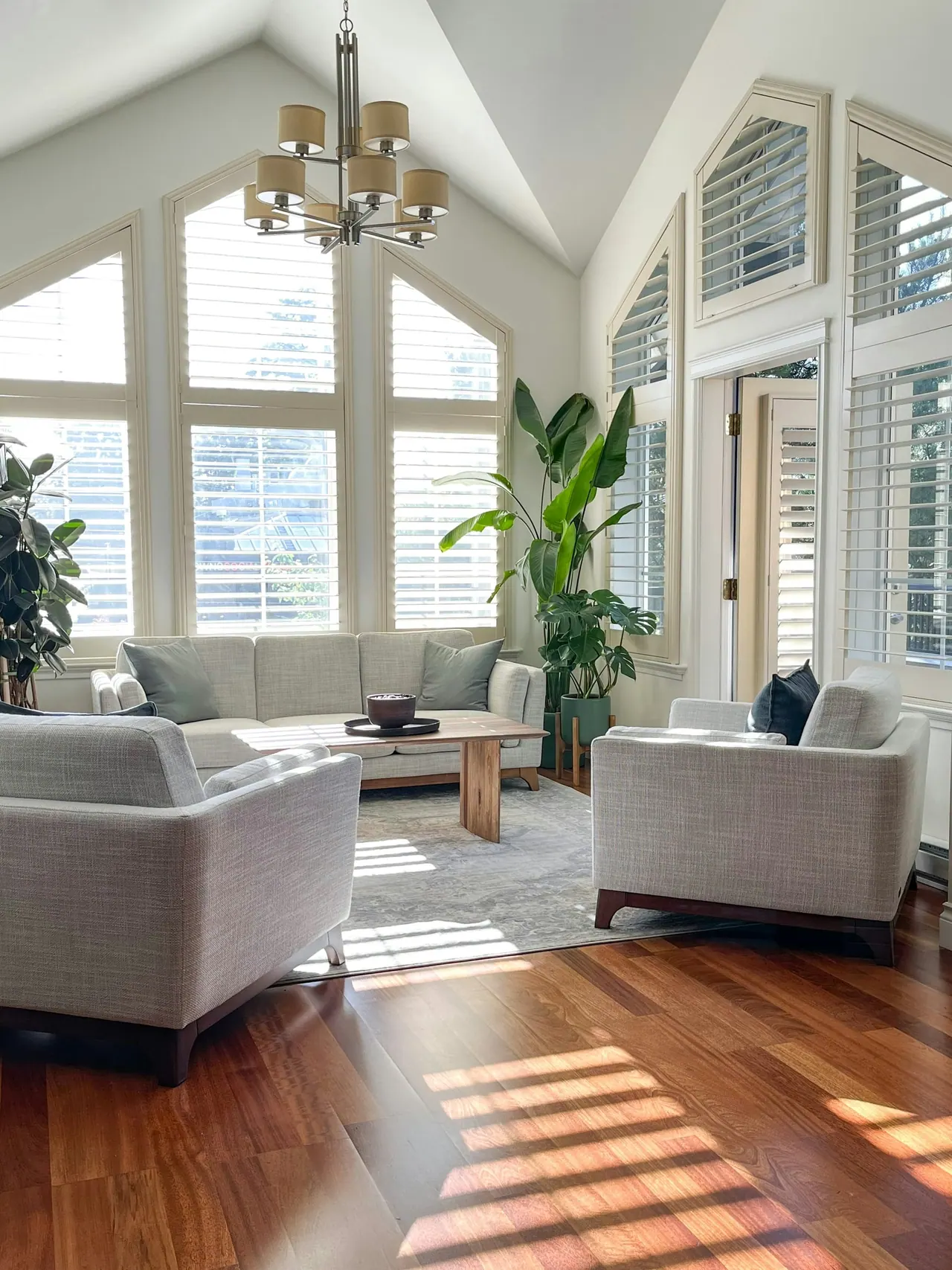A sunlit living room under a vaulted ceiling with tall arched windows