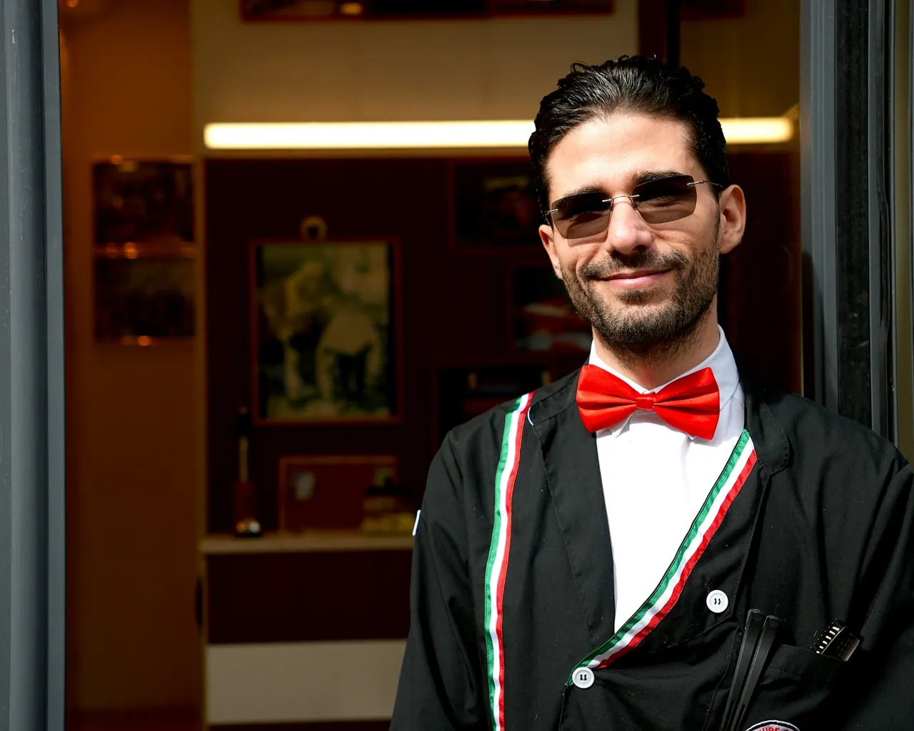 A smiling server in a red bow tie at the door