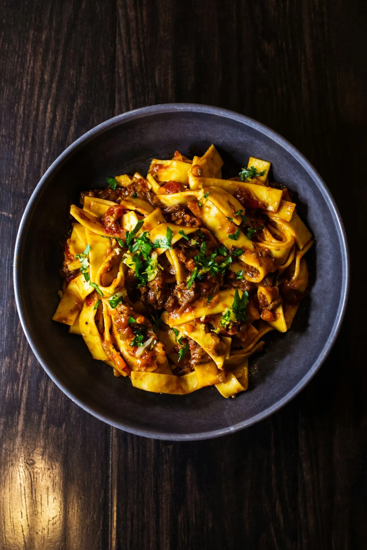 Ribbons of fresh pasta with slow braised beef in a dark bowl