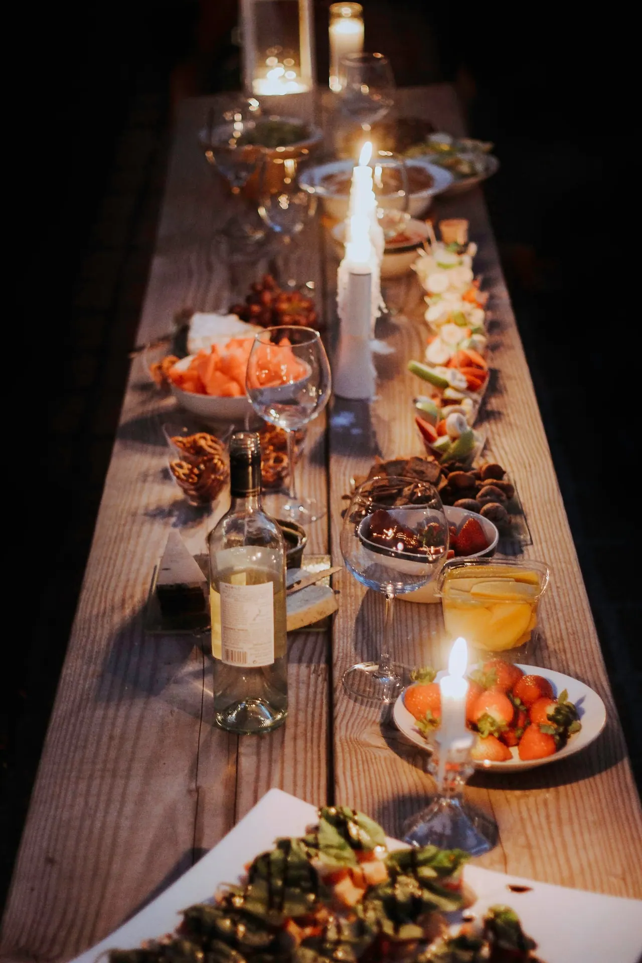 A long candlelit table laid with plates and glasses