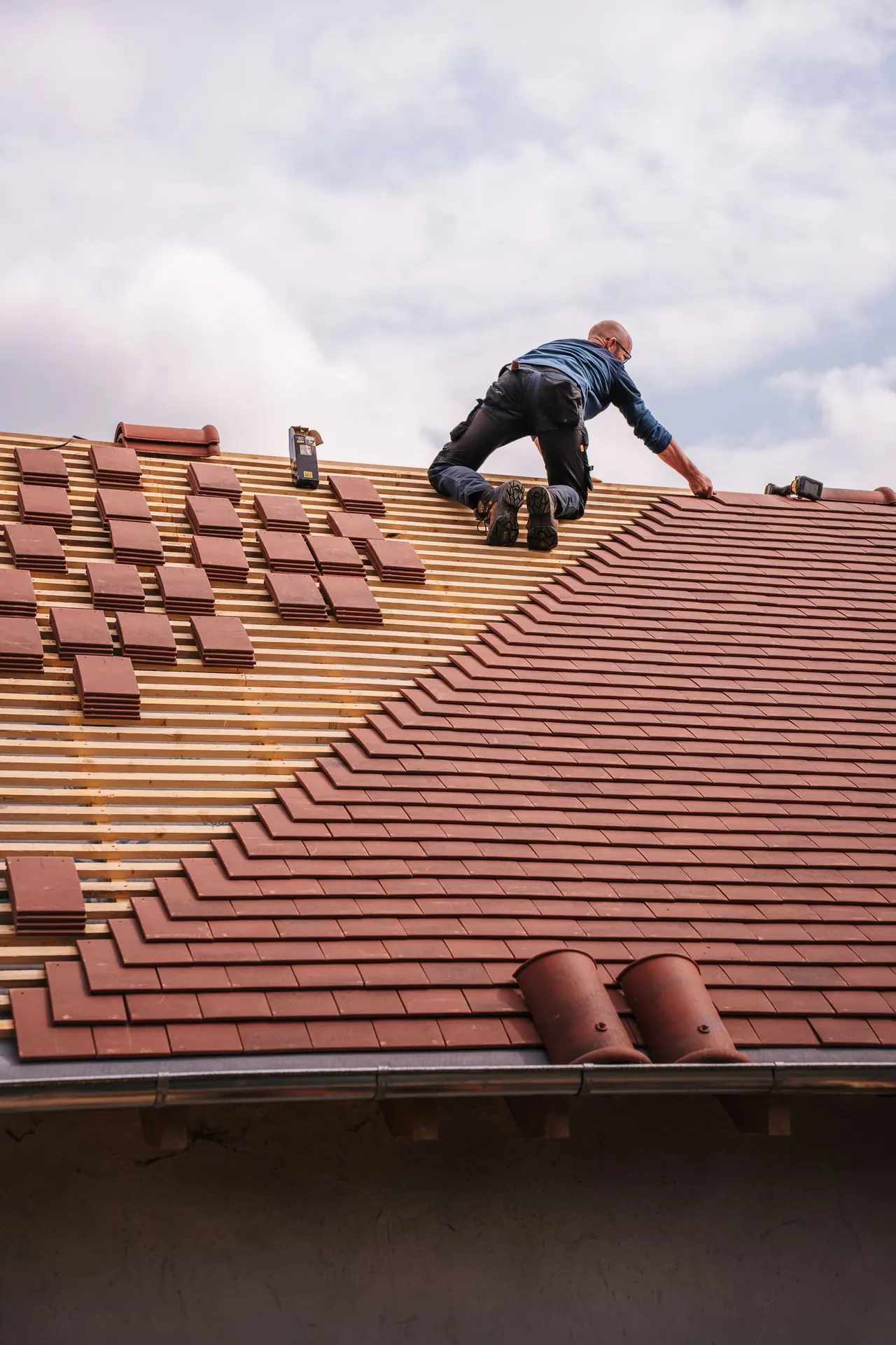 A roofer laying new clay tiles