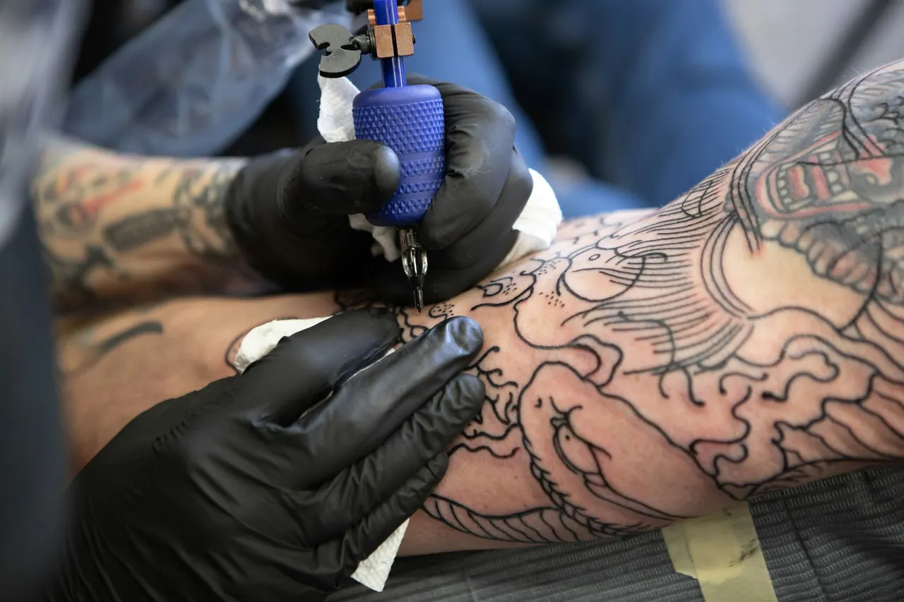 An artist in black gloves lining a large, detailed arm piece