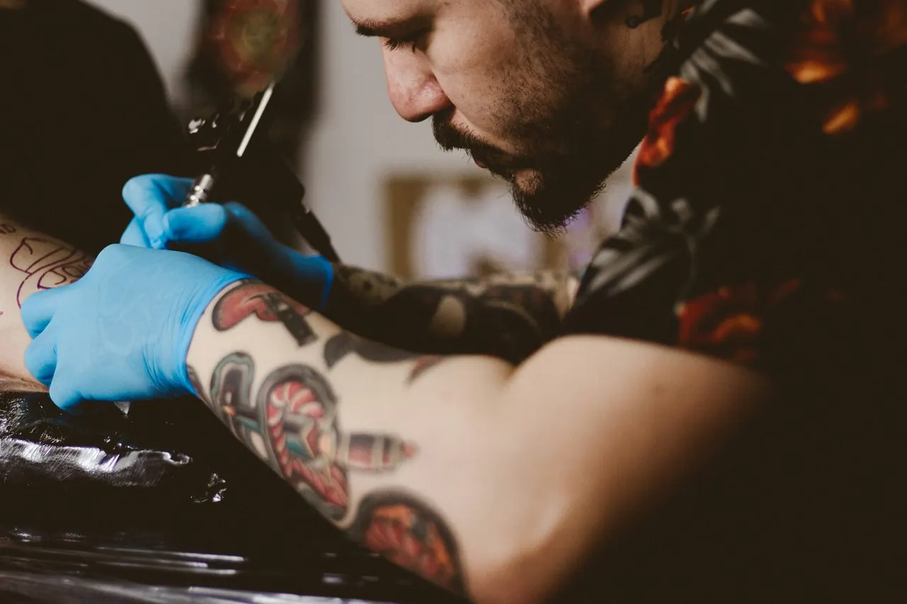 A bearded artist in blue gloves concentrating on a colour sleeve