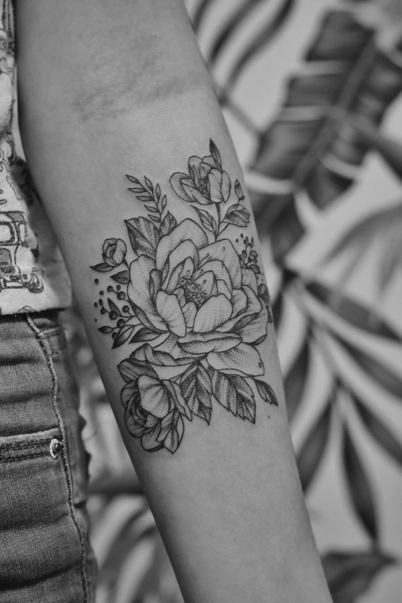 A black and grey floral tattoo on a forearm