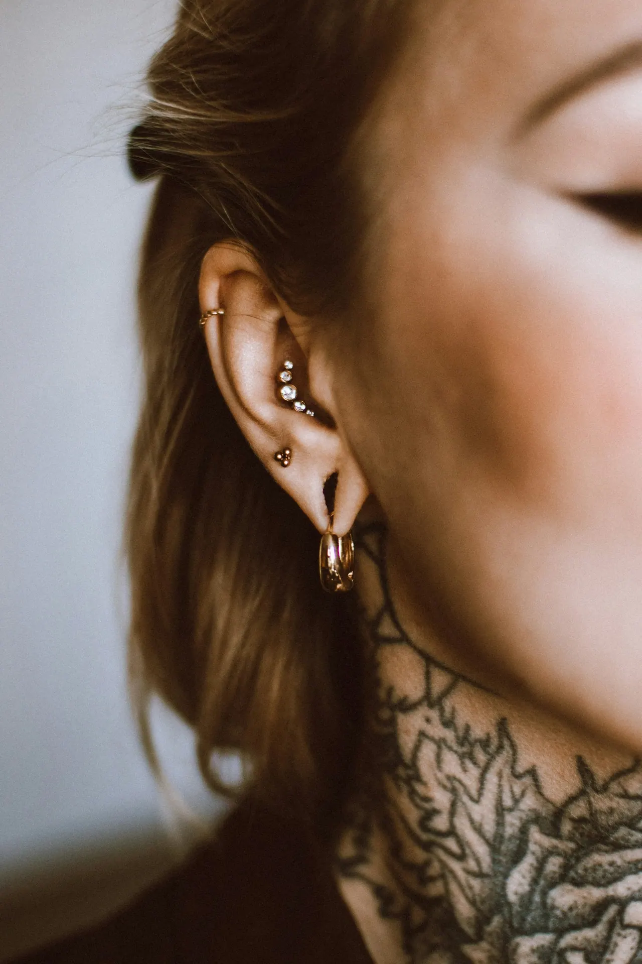 A client in profile with stacked ear piercings and a fine line neck tattoo