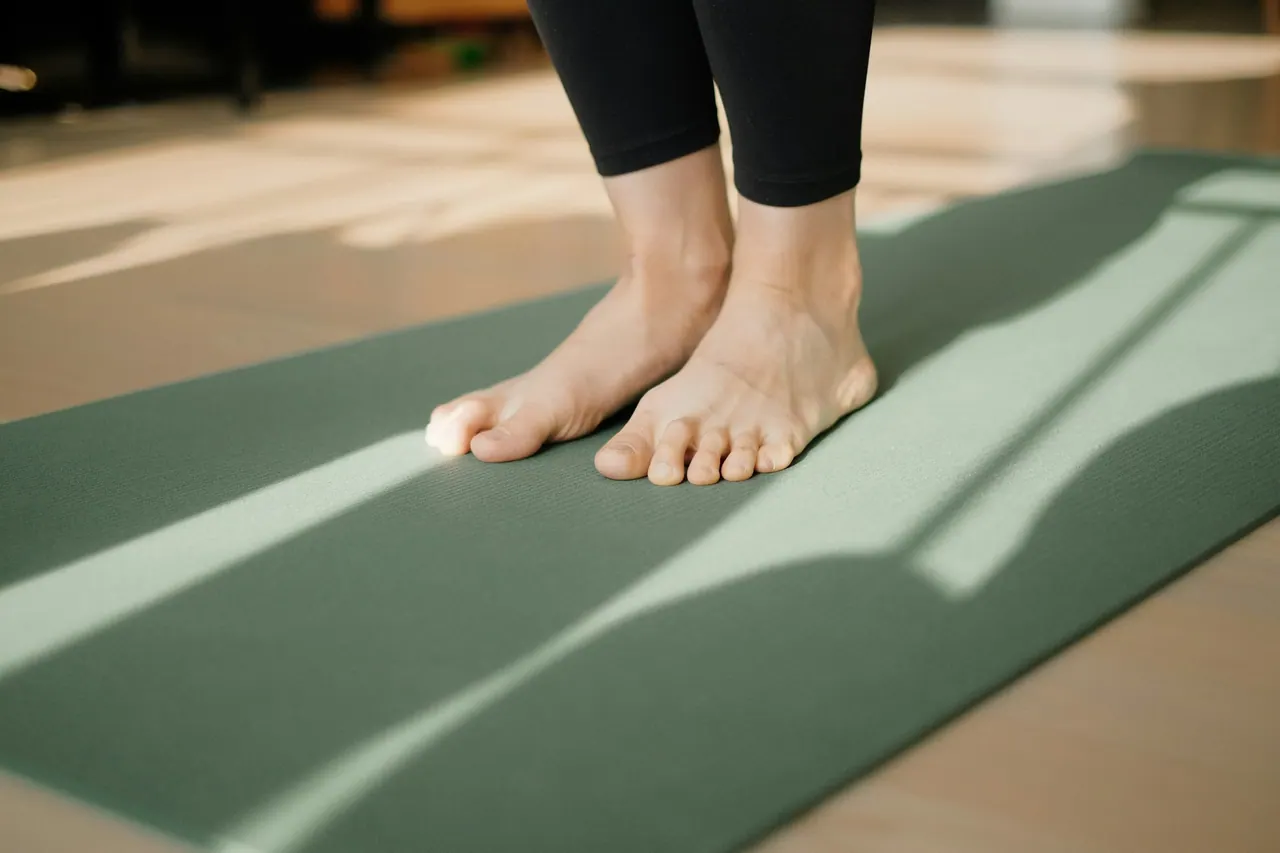 Bare feet standing on a green mat in morning light
