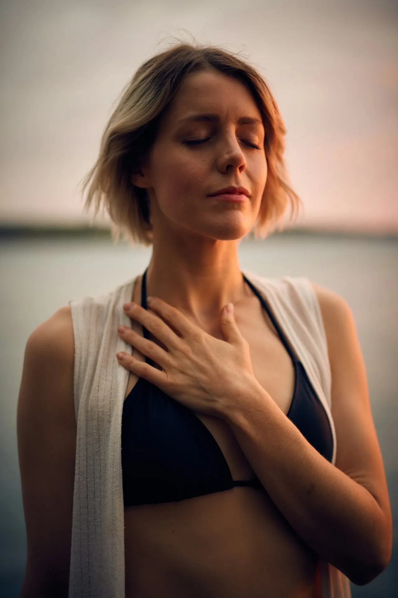 A woman breathing slowly with one hand on her chest at dusk